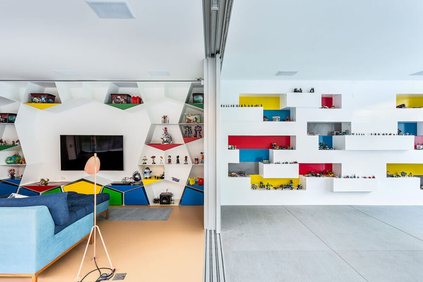 这一层的客厅以独特的多边形搁架墙为特色，点缀着明亮的原色。右边是独特的“乐高”墙，内置的架子上放着数百个玩具。