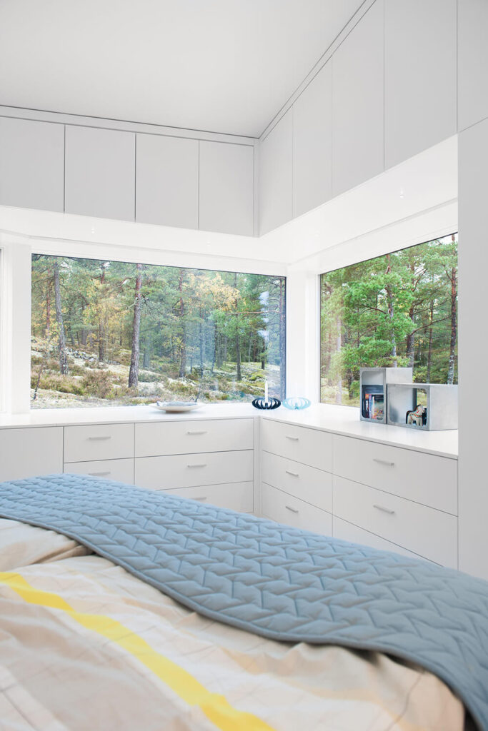 卧室设有一套内置橱柜和抽屉，巧妙地混合在存储选项。大的角落窗户提供了更广阔的室内自然景观。