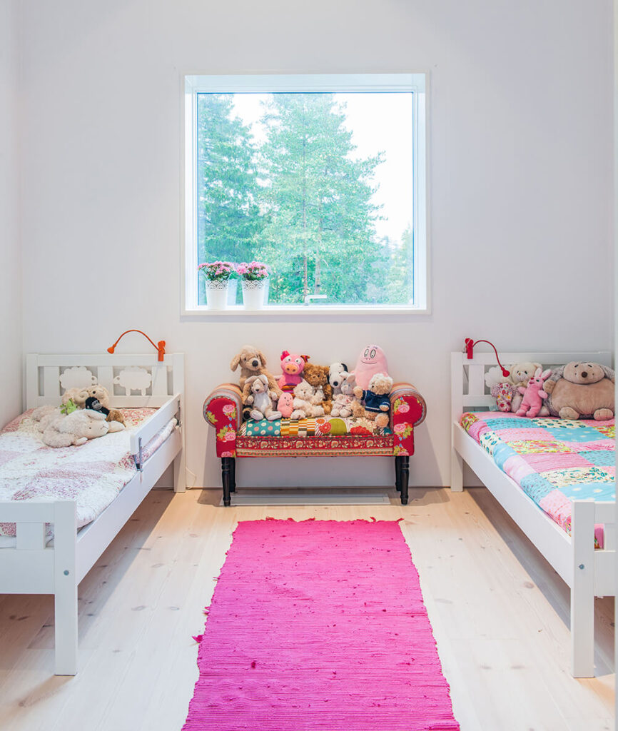 这个儿童卧室的特点是更微妙的亮色飞溅，包括中央醒目的粉红色地毯。如图所示，整个住宅的大窗户为设计明亮的室内提供了大量的自然光线。