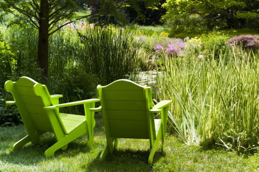 春天绿色的阿迪朗达克椅子俯瞰池塘。