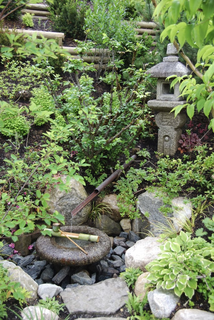 岩石和石头经常用于亚洲风格的园林绿化。在这里，我们可以看到一个隐藏在小岩石花园里的传统日本水景。这是一个聆听舒缓的流水声在大自然中冥想的好地方。