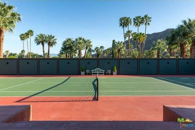 这是一个网球场，有着高大的混凝土墙和高大的棕榈树。图片来自Toptenrealestatedeals.com。