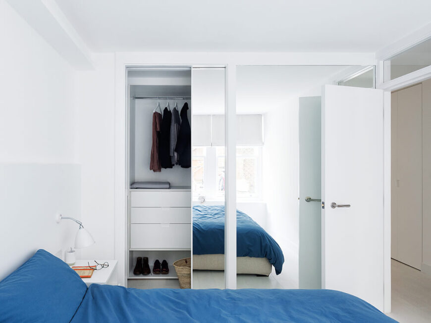 卧室利用墙壁大小的大镜子来帮助视觉上扩大它的大小。门廊上方的小窗户将连接延伸到住宅的其他部分。