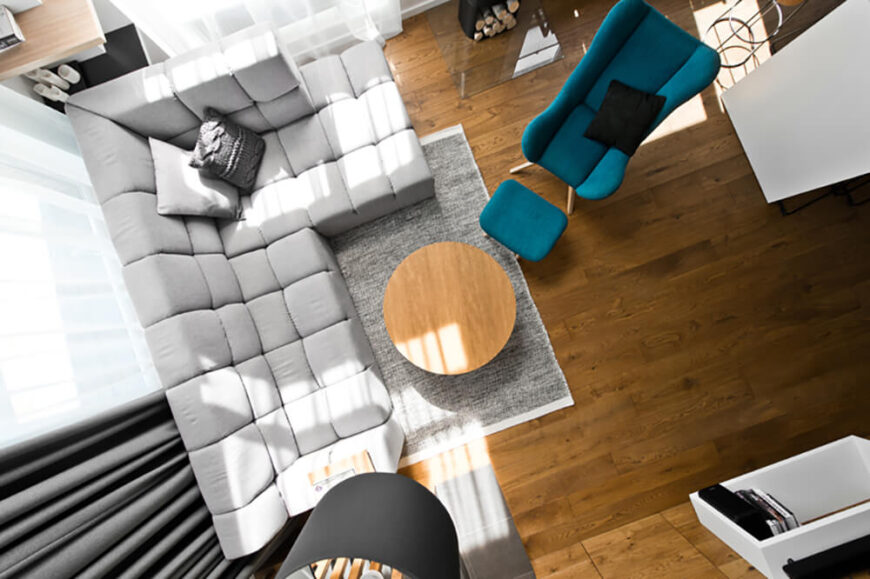 在客厅的俯景中，我们可以很容易地看到有品位的家具的平衡布置，与丰富的硬木地板形成中性的色调。一张蓝色的单人扶手椅和一张土耳其脚凳给这个房间增添了色彩。