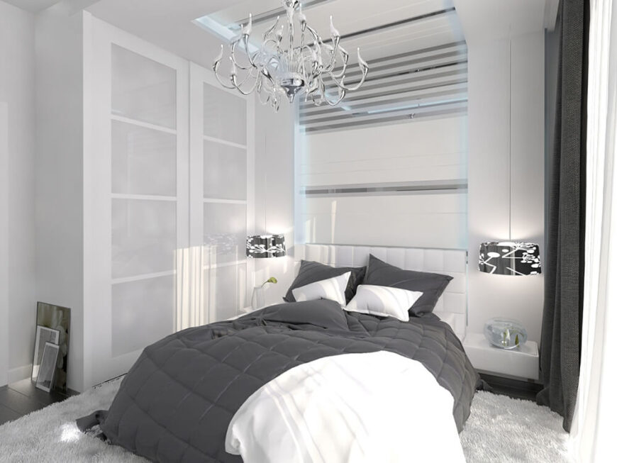 这间卧室用传统风格的光滑镀铬吊灯突出了大胆的白色现代主义风格。白色的墙壁和储藏室与深灰色的床上用品、窗帘和地板形成了强烈的对比。