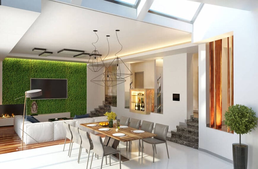 向客厅区域望去，我们看到一个平板电视安装在通高的生活墙上，周围是绿色植物，从上方照明。这个令人吃惊的元素赋予了现代空间更有质感、永恒的吸引力。