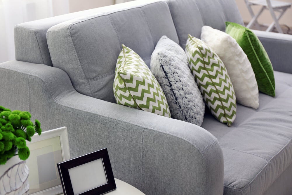 有灰色，白色和绿色的灰色沙发在重叠的多米诺形成的枕头。