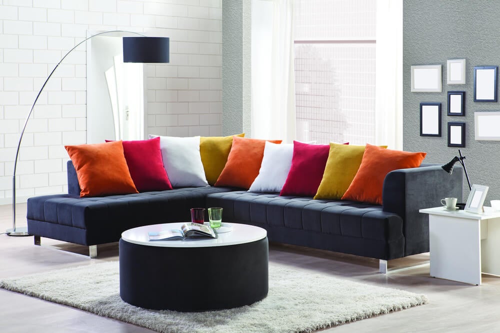 深蓝色截面沙发的例子，衬到许多明亮，坚实的枕头 - 橙色，红色和白色 - 以重复的模式。