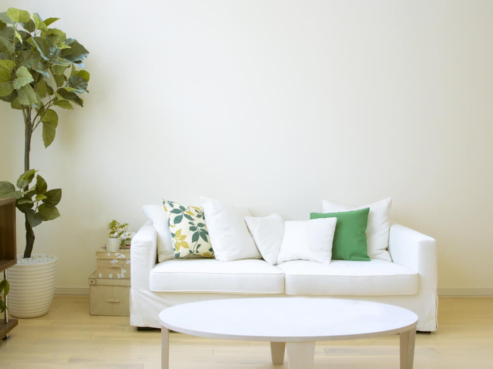 白色长沙发用一个花卉枕头，5个坚固的白色枕头和一个坚固的绿色枕头。