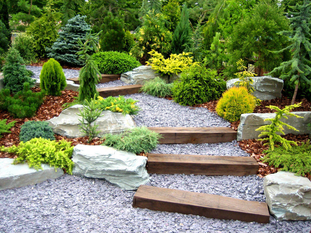 修剪整齐的各种常绿灌木为花园的鹅卵石台阶和偶尔的木板让路。一些漂白颜色的巨石也被用在灌木之间，以留出足够的空间。