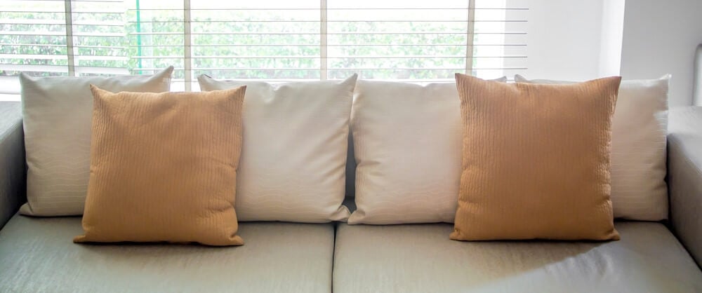 沙发，扔枕头沿着后面衬里，上面有2个棕色枕头，为一个对称的枕头设计。