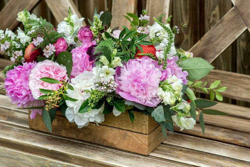 一个精心制作的木质花盒里摆放着粉红色和白色的花朵。