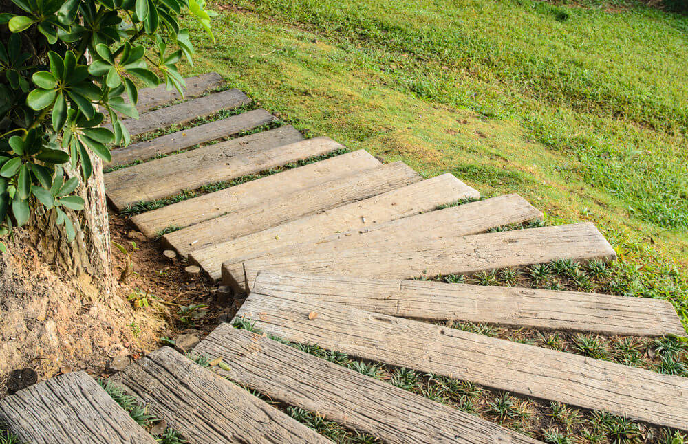 这些花园台阶由木板组成，在绿色的草坡上绕着弯道向下弯曲。