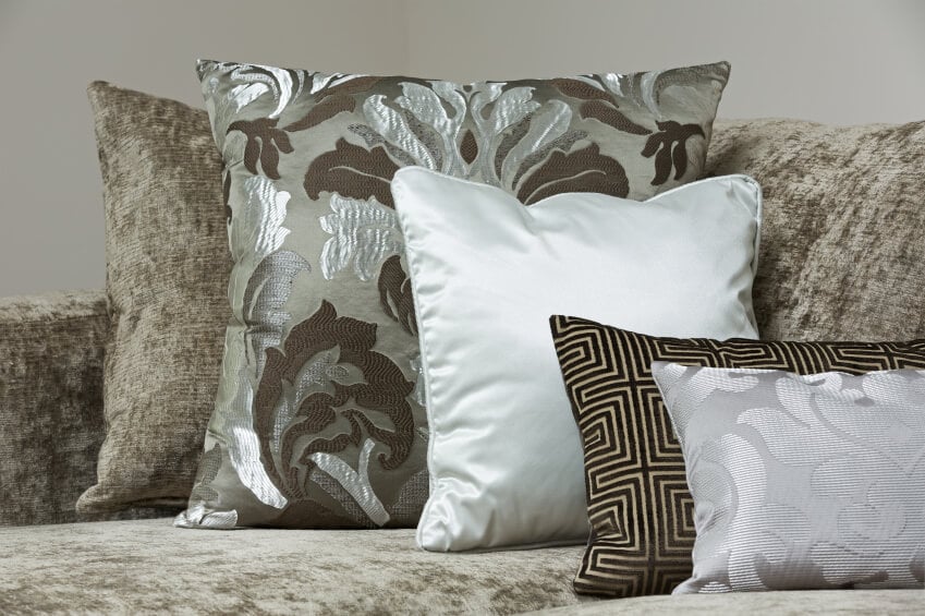 拉丝深绿色和浅灰色的沙发样式与语气的类似枕头。这种枕头布置用几种光滑的枕头织物来抵消平面刷沙发面料。