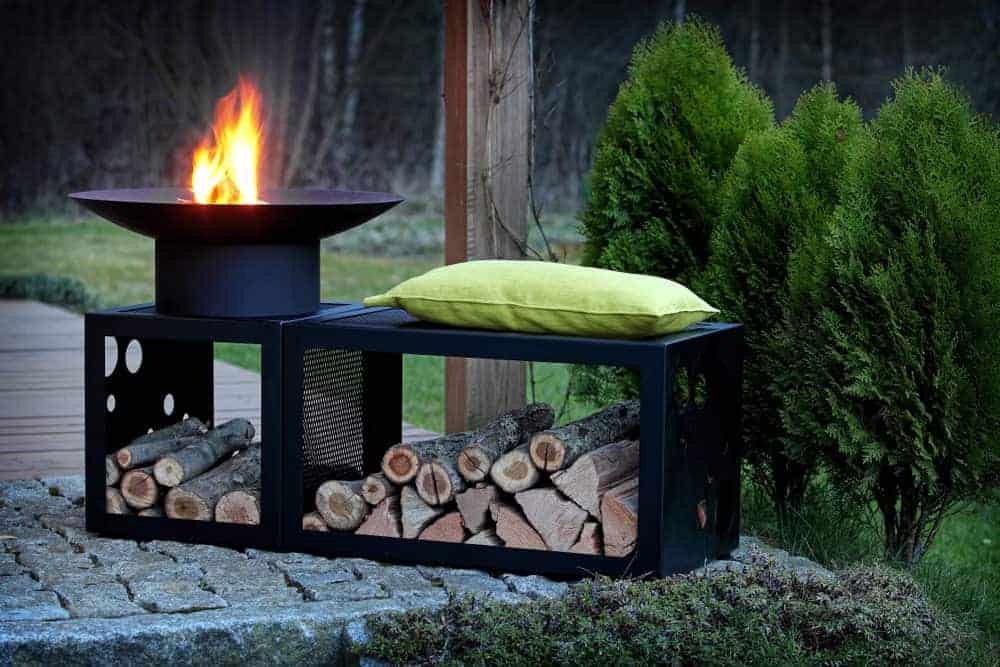 黑色金属圆形火坑与木材储存和长凳。