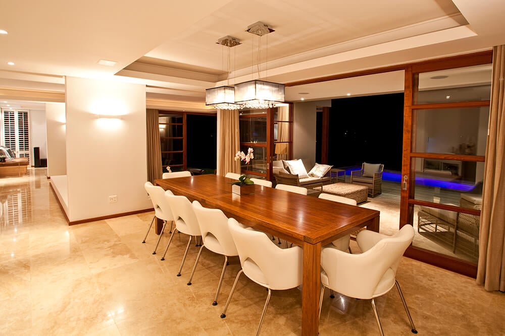 用餐区设有矩形餐桌，托盘天花板下有白色椅子，配有一对现代的吸顶灯。