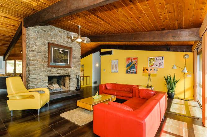 客厅里的亮橙色皮革沙发与黄色扶手椅、中央桌子和墙壁并列，非常令人惊叹和明亮。