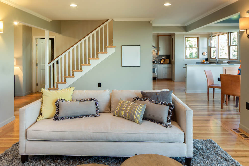近距离看一下这个客厅的沙发，上面铺着灰色的地毯，覆盖着硬木地板。