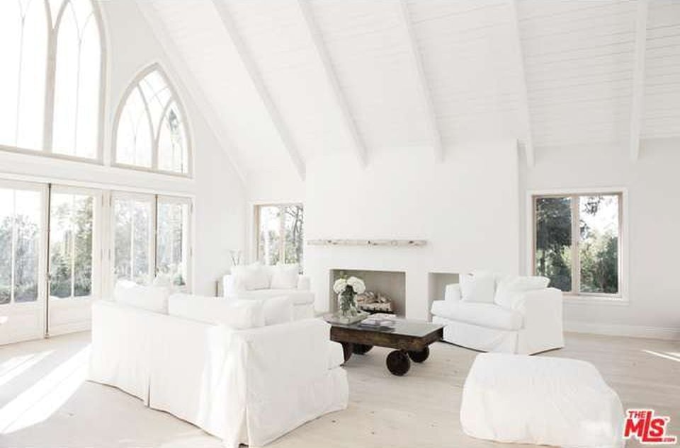 一个非常宏伟的白色客厅，一个木制轮式中央桌子突出了自然的棕色阴影。