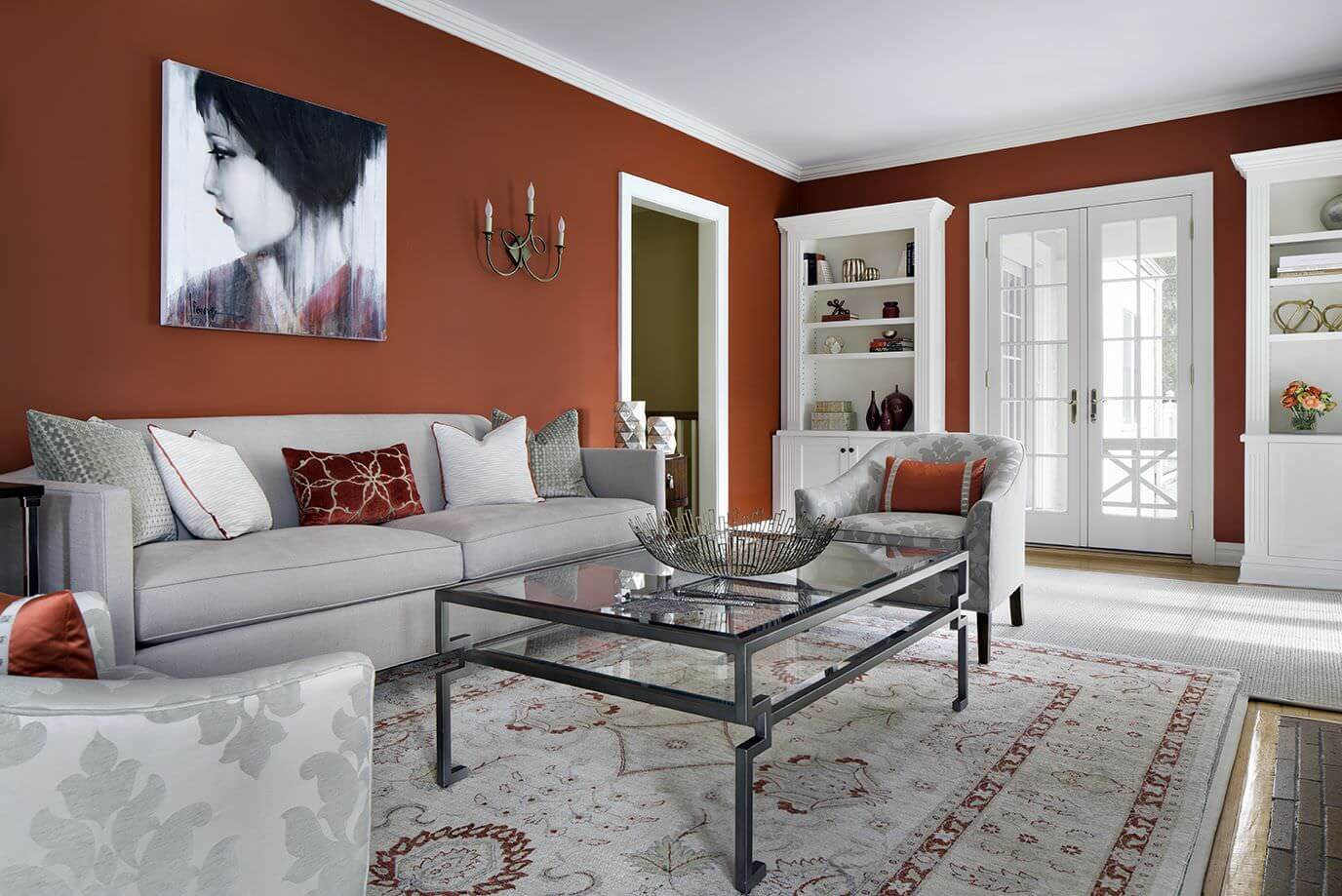 宽敞的起居空间以质朴的红色墙壁以及白色的书架和灰色的座椅为特色。