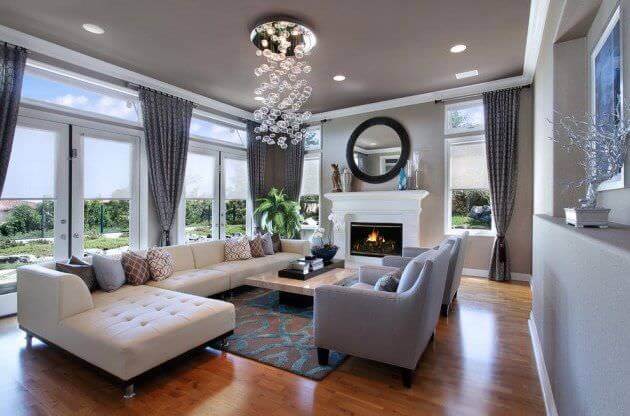 这间客厅以硬木地板和灰色墙壁为特色。它配有一张长长的l型沙发、灰色座椅和一座壁炉。