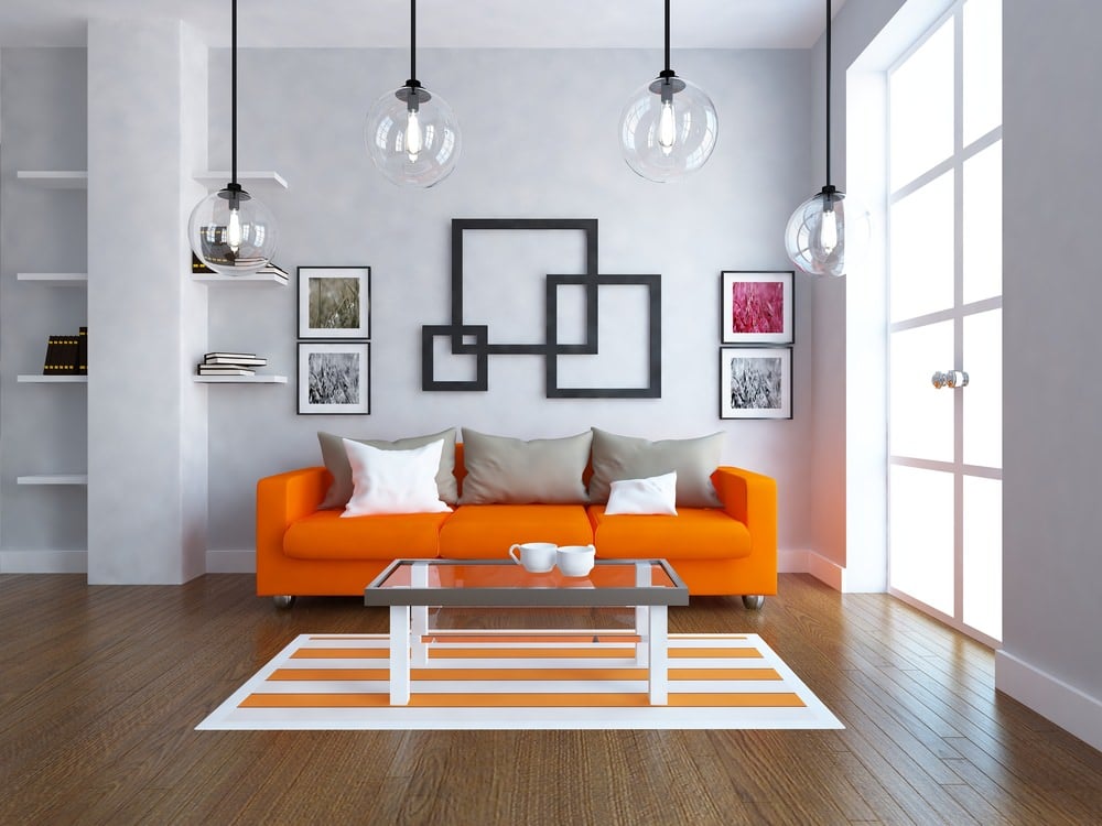 这是一个令人惊叹的当代设计与简单的表面和形式。明亮的阳光从一扇大玻璃门照射进来，映照着橙色的沙发套装和木地板上的橙色花纹地毯。