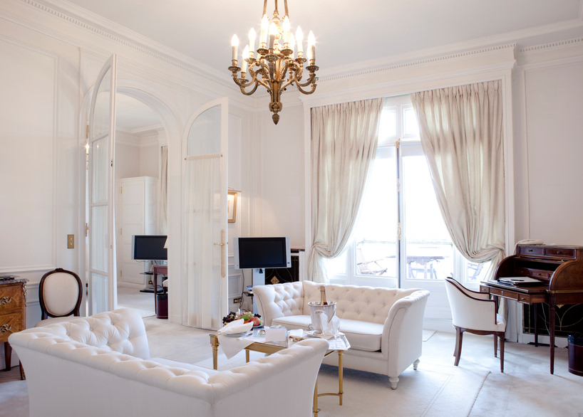 这是一个相当传统的客厅，从地板到天花板都是白色的。窗帘是白色的，地毯是白色的，沙发也是白色的。然而，与柜子和钢琴组的深色木材形成了一些对比。