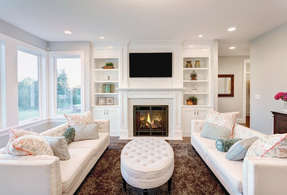 这个客厅定义了一个纯白色的云，一些添加的装饰口音，如框架和鲜花，给一点对比和颜色。配套的沙发套和脚凳在棕色粗毛地毯上创造了一个舒适的空间。