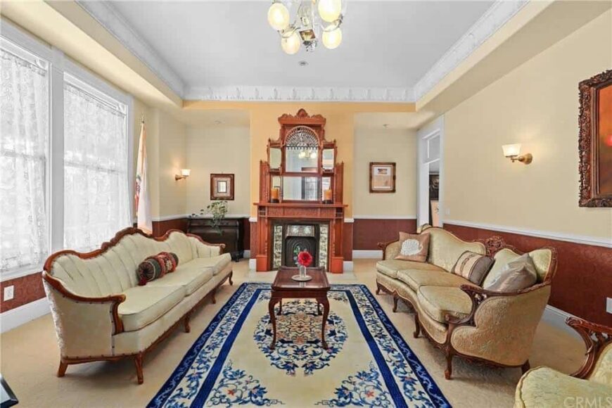 这间客厅设有舒适的沙发组和地毯上的小木桌。它也有壁炉和一个华丽的墙壁装饰。