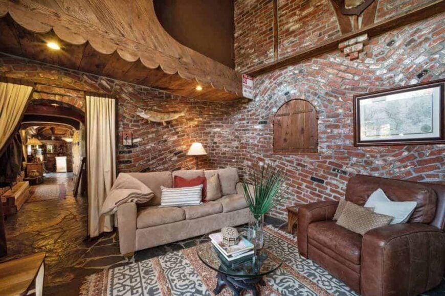 这个简单而质朴的客厅由华丽的起伏红砖墙补充，为沙发和皮革扶手椅设置了可爱的背景。