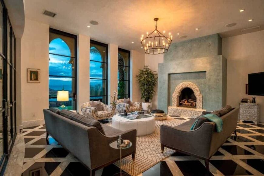 这间客厅设有舒适的沙发组和地毯上的圆桌。这个起居空间因令人眼花缭乱的枝形吊灯而变得明亮，它还有一个壁炉。
