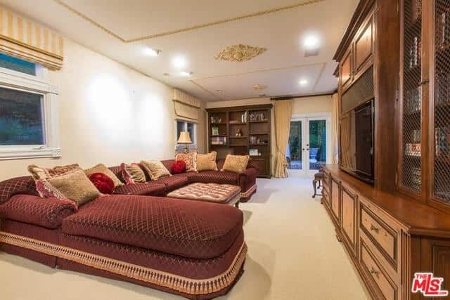 这个客厅有一个u型舒适的沙发，中间有一张皮革桌子。屋内还有木质橱柜，橱柜顶部还有一台电视。
