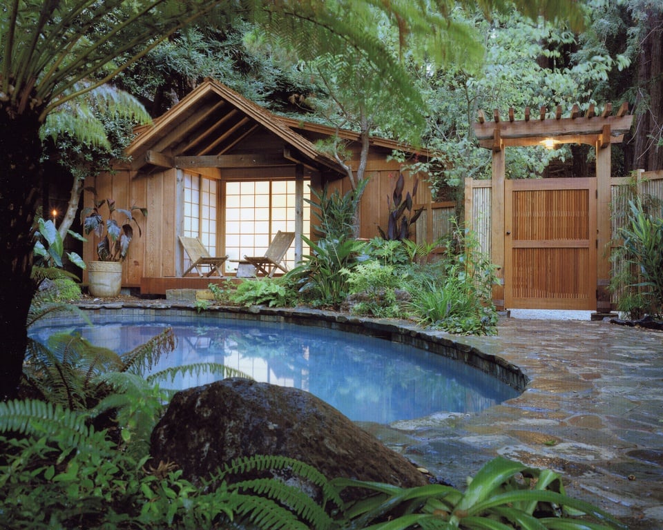 这是一个很好的亚洲风格后院的例子，有亚洲设计的台球厅和花园，周围有一个肾形的小游泳池。