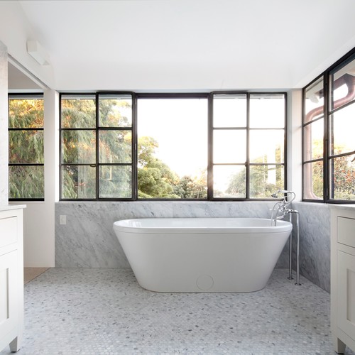 一间宽敞的浴室，配有独立浴缸，灰色大理石墙壁和灰色卵石瓷砖。/摄影:Decus Interiors