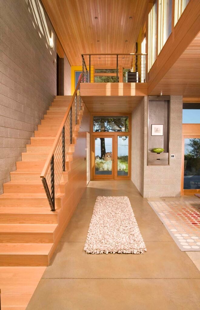 釉面入口以瓷砖地板为特色，顶部有一个蓬松的跑道和木制楼梯，钢制栏杆固定在灰色砖墙上。