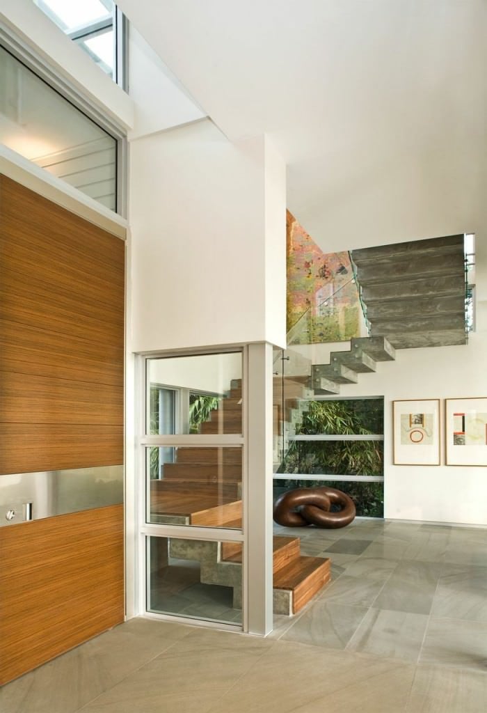 门厅以瓷砖地板和白色墙壁为特色。楼梯是夹层的，与房子的玻璃门窗完美契合。