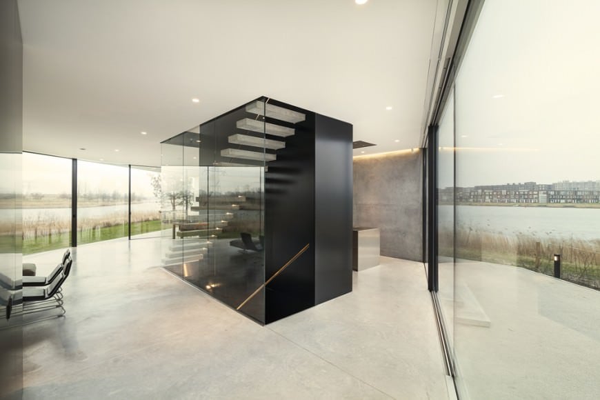 现代门厅展示了全景窗户与惊人的户外风景和黑色楼梯安装无框玻璃板。