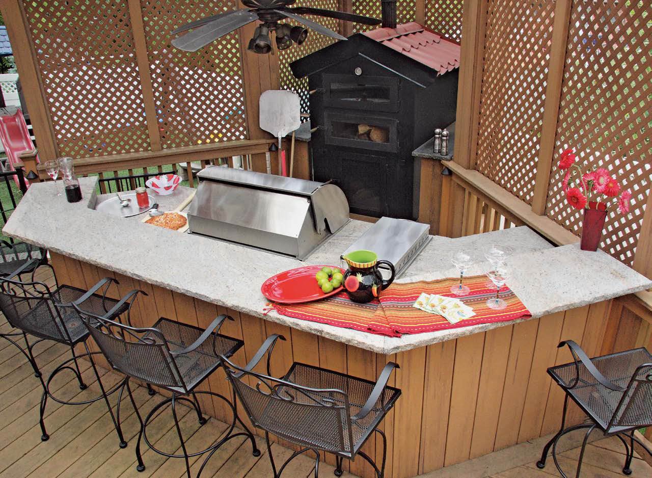 这间户外厨房设有一个带大理石台面的柜台和一个供四人用餐的早餐吧台。