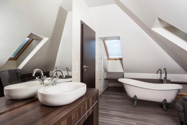 现代主浴室设有白色墙壁和天花板以及硬木地板和硬木水槽柜台。这间客房还设有一个独立浴缸和一个水槽。