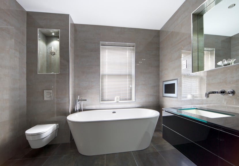 主浴室设有灰色瓷砖墙壁和地板，以及高高的天花板。房间里有一个独立的浴缸和一个时尚的浮动洗手池。