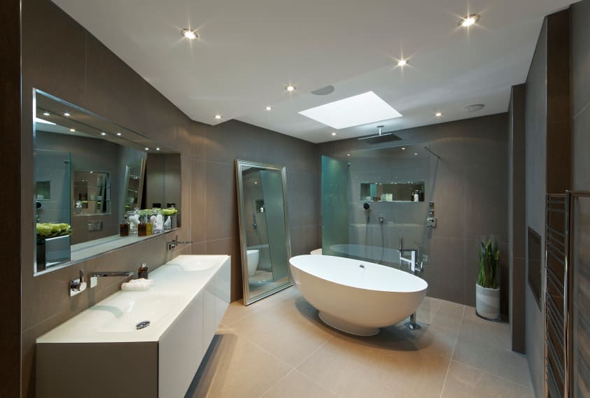 现代主浴室采用灰色瓷砖墙和带天窗的白色天花板。该房间设有一个浮动洗手池、一个独立浴缸和一间步入式淋浴间。