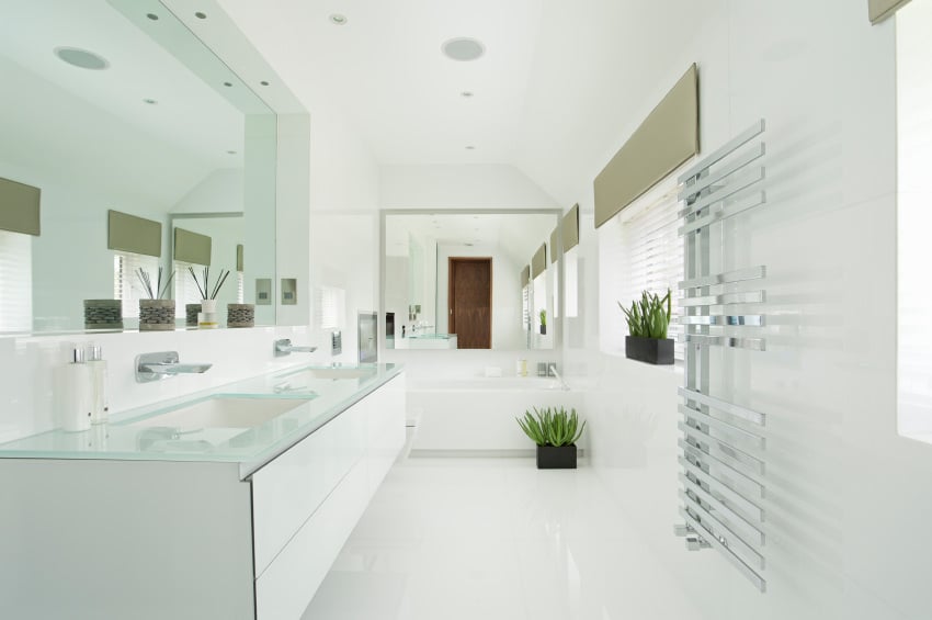 明亮的主浴室带有令人惊叹的双水槽，周围环绕着白色墙壁和白色地板。