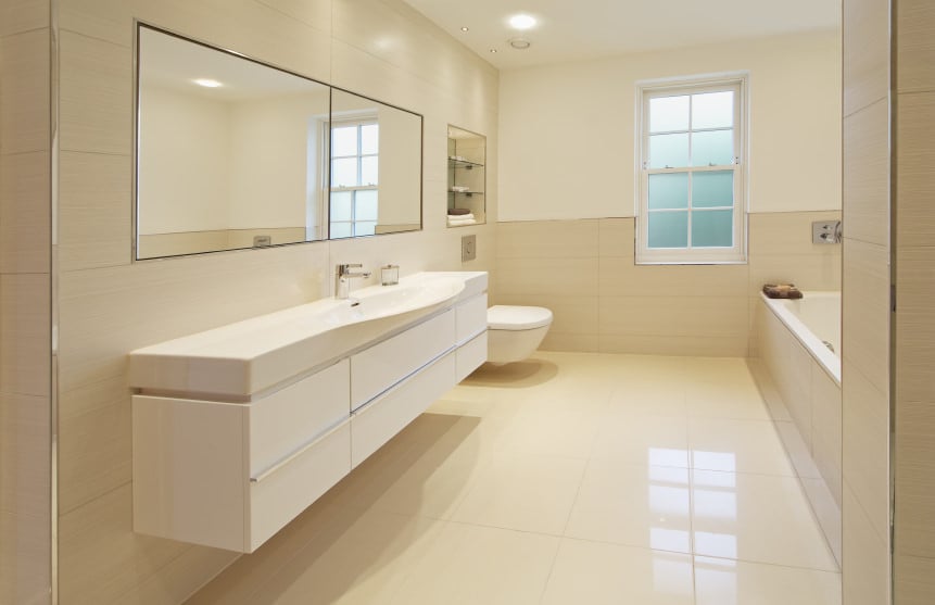 这间主浴室设有一个深泡浴缸和一个浮动洗手池，四周铺着瓷砖地板和米黄色墙壁。