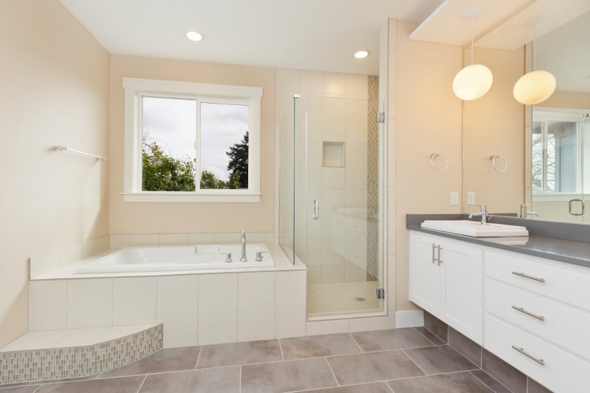 迷人的浴室有一个白色的浮动洗手台，由一个圆形吊坠照亮，挂在内置的架子上。在铺着白色瓷砖的浴缸旁边，还有一间步入式淋浴间。