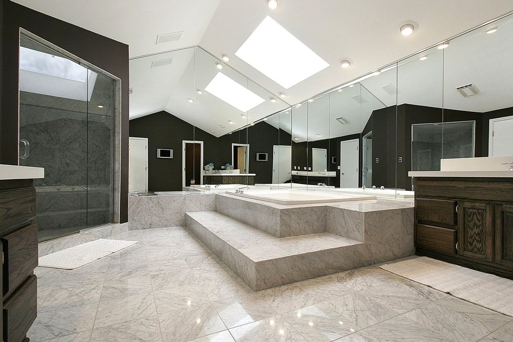 一个巨大的主浴室，拥有大理石瓷砖地板和一个带天窗的拱形天花板下的大型深层浴缸。