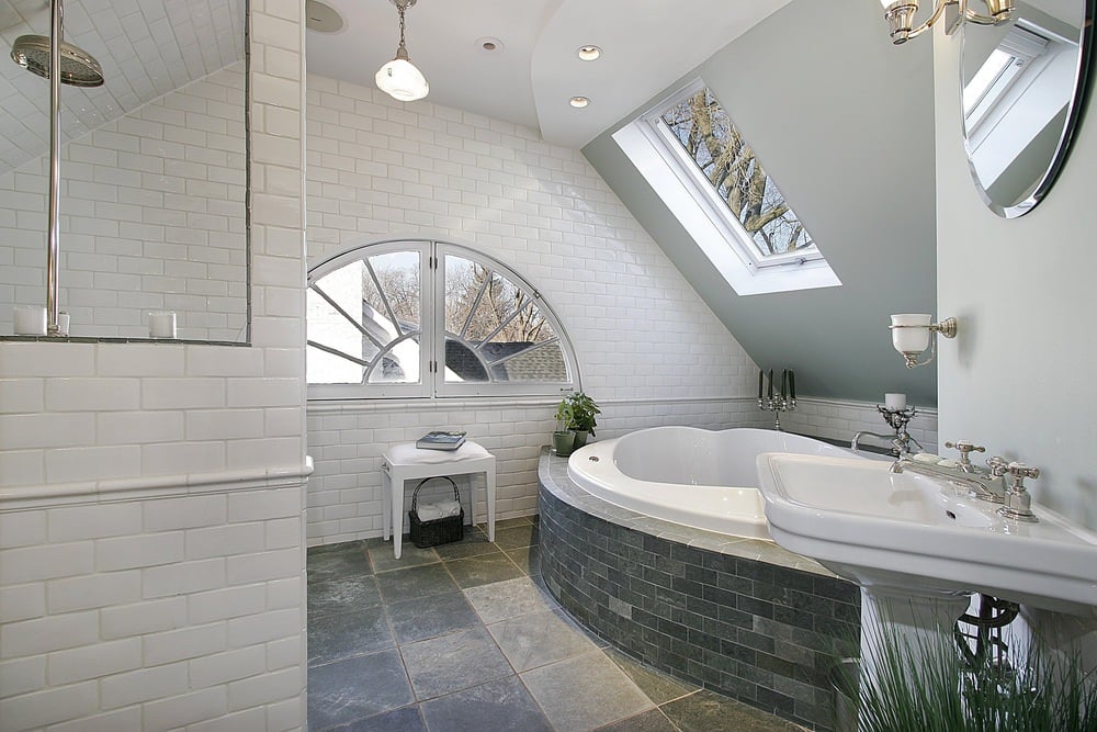 这间主浴室拥有时尚的瓷砖地板，一个大浴缸和一个底座水槽。