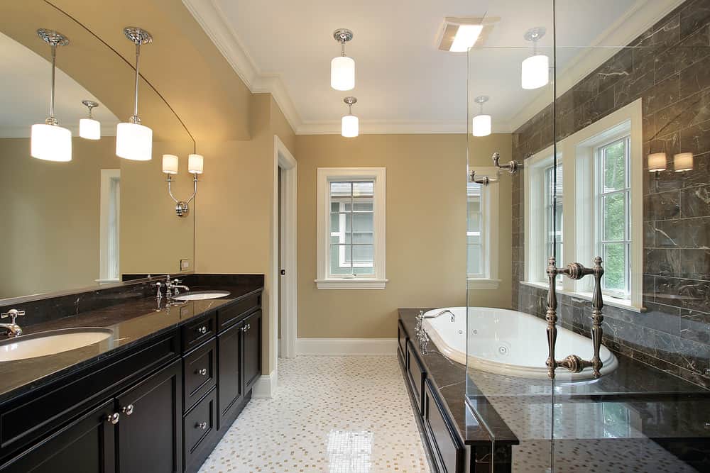 精致的浴室，黑色双洗手池梳妆台与浴缸周围的瓷砖相辅相成。它有白色图案的地板和米黄色的墙壁，配有白色框窗。