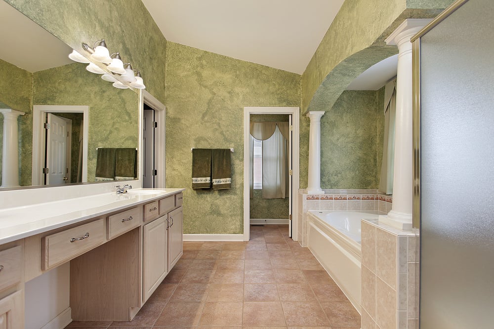 主浴室带有一个可随意使用的浴缸，四周环绕着绿色的墙壁和棕色的瓷砖地板。
