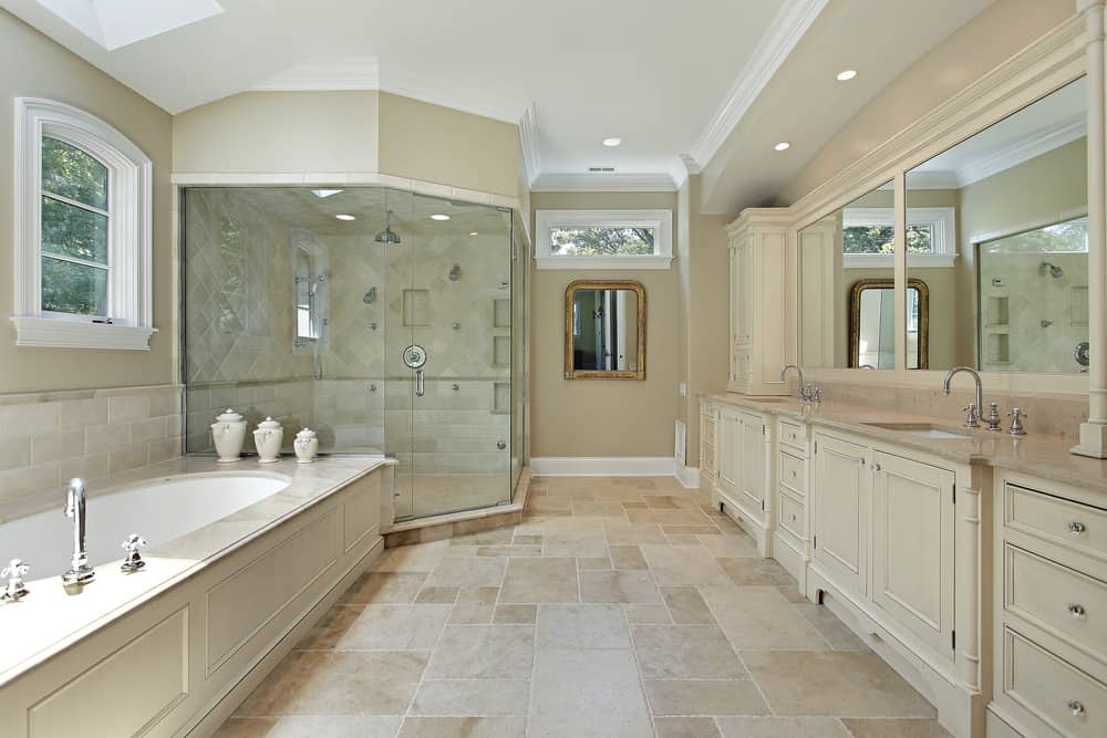 大主浴室，侧面有浴缸，角落里有步入式淋浴。米色的瓷砖地板和嵌壁灯看起来很完美。