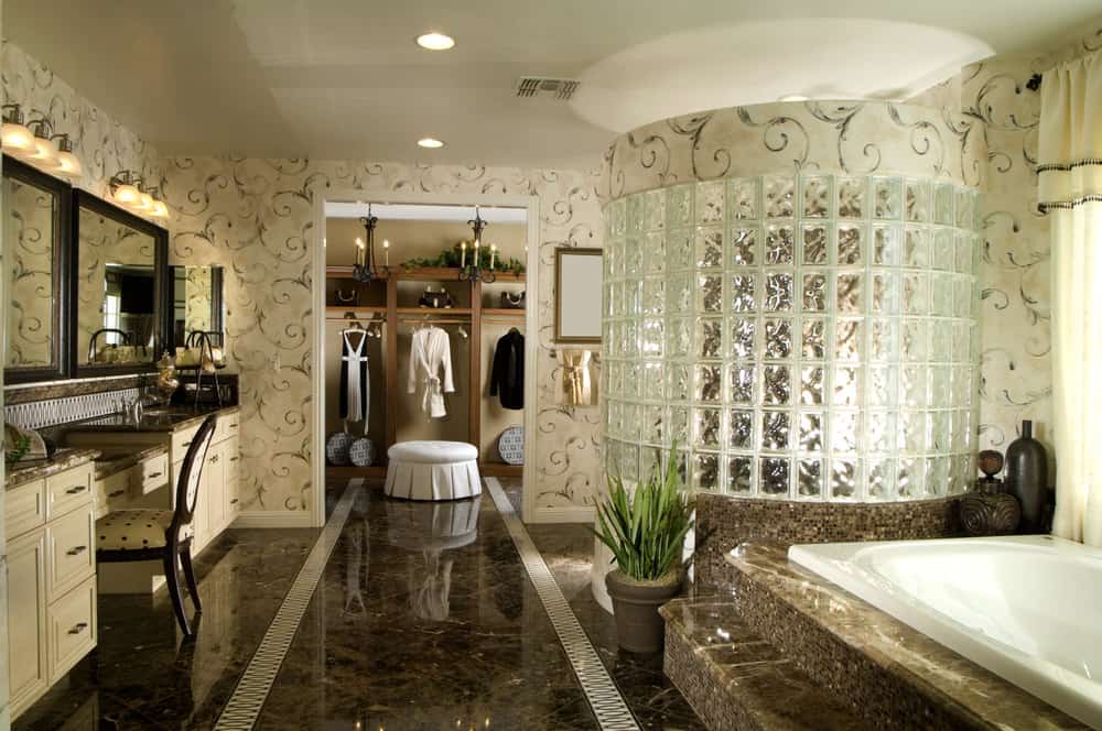 主浴室四周环绕着优雅的墙壁和瓷砖地板。步入式淋浴房和大理石平台上的浴缸看起来很豪华。